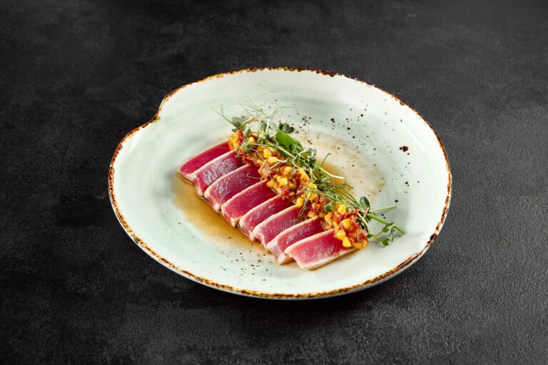 Seared tuna tataki with mango salsa and ponzu sauce on a speckled ceramic plate