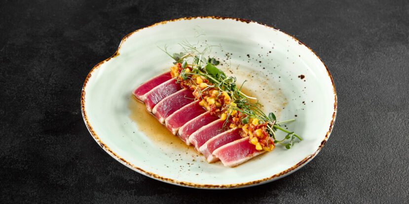 Seared tuna tataki with mango salsa and ponzu sauce on a speckled ceramic plate